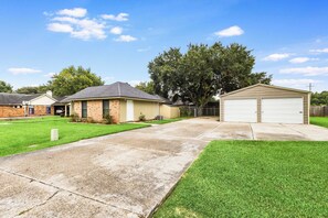 A residential property with a paved driveway, a garage, and a lawn. - NEW! Kid Friendly 3BR Fenced Yard - Sports Complex (Youngsville)