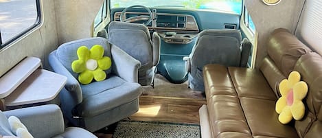 Interior compacto de una caravana con kitchenette, zona de estar y una mesita.