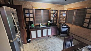 A kitchen with a refrigerator, sink, stove, and wooden cabinets.