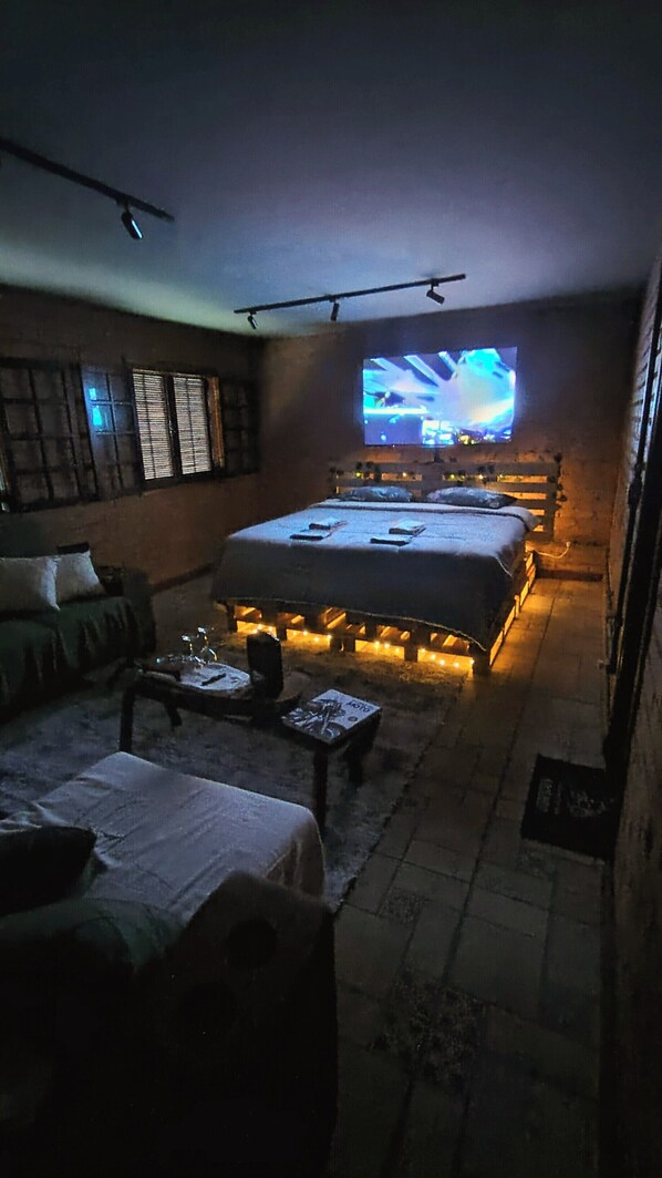 A dimly lit room with a bed, a television, and a sofa.