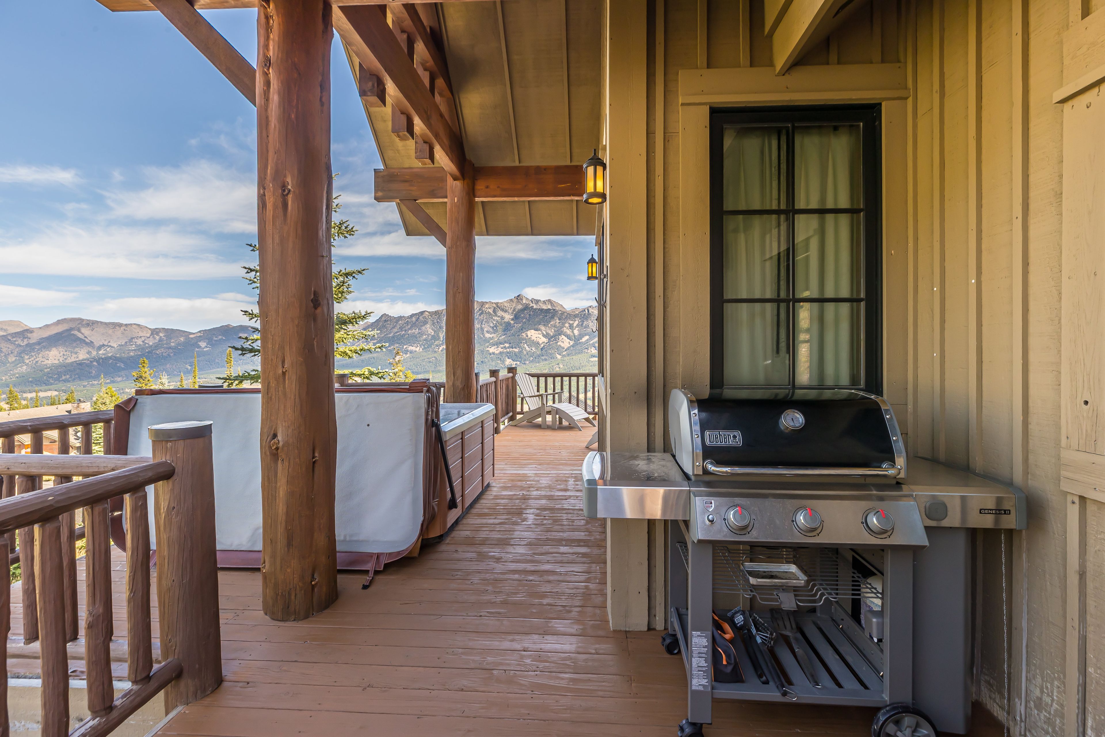A wooden deck with a barbecue grill, a covered hot tub, and a view of mountains.