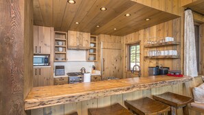 Cocina de madera con barra, taburetes y electrodomésticos integrados.
