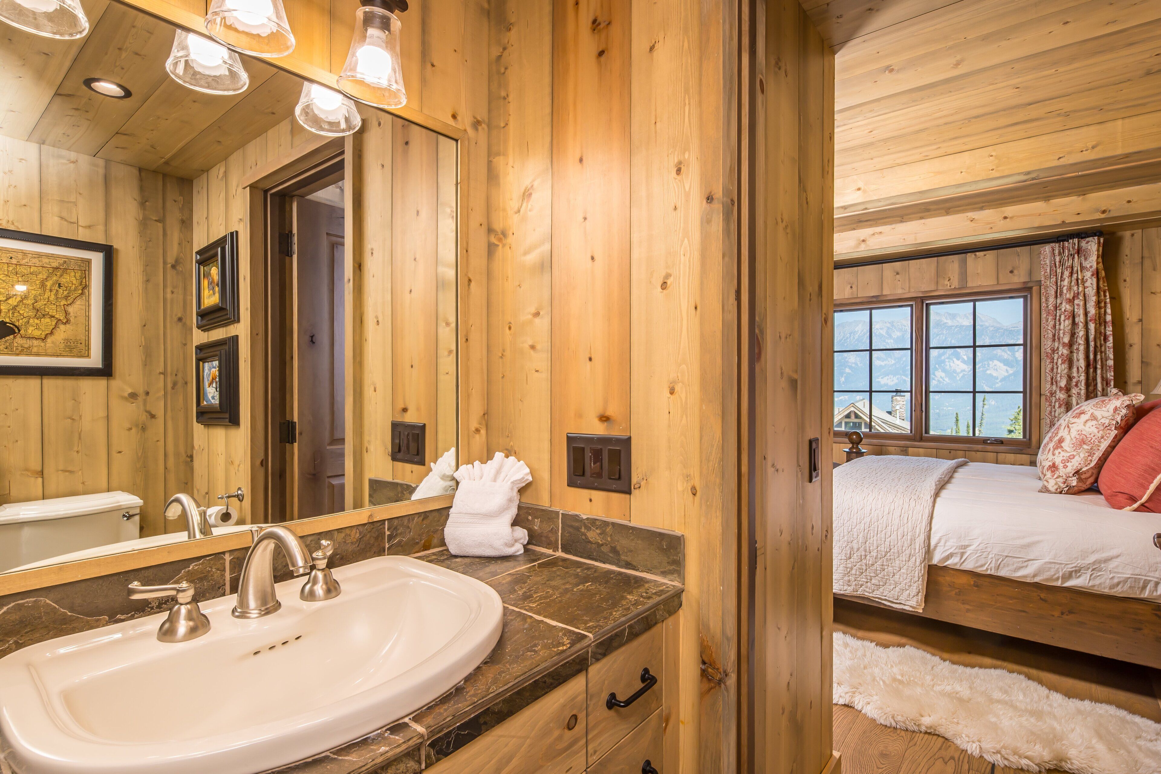 A wooden cabin interior with a bathroom featuring a sink, mirror, and towel hanging on the wall.