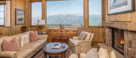 Una sala de estar acogedora con chimenea, muebles de cuero y vistas a la montaña.