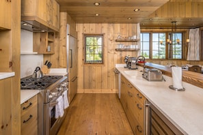A wooden interior with a kitchen area featuring a stove, sink, and various utensils.