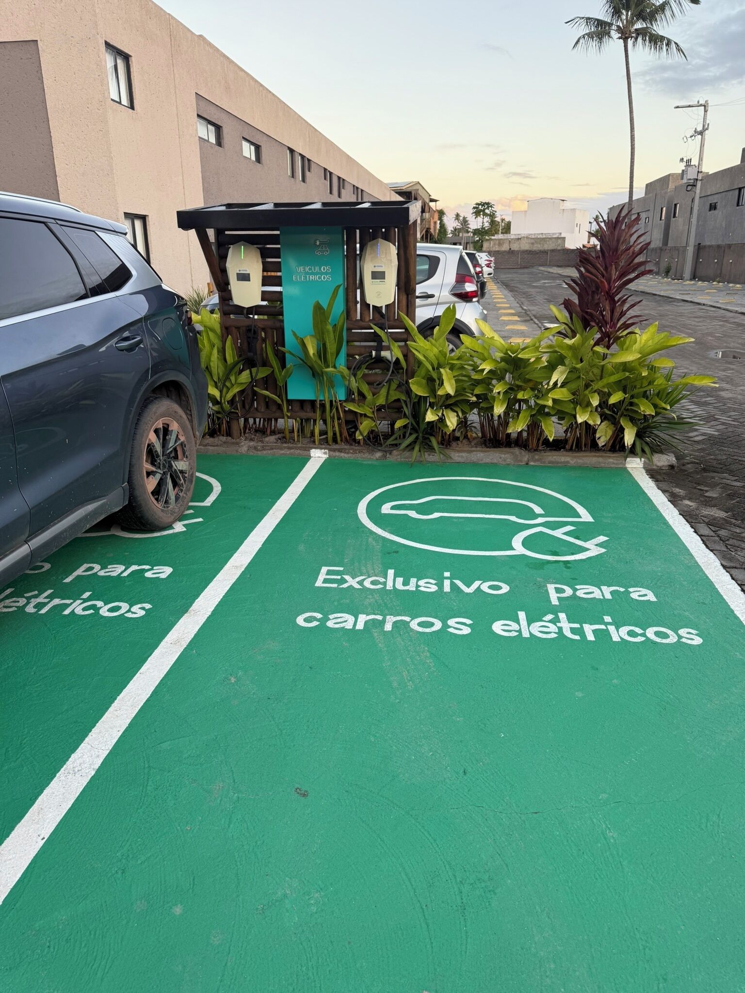 Uma área de estacionamento com pintura verde indicando uma vaga reservada para veículos elétricos.