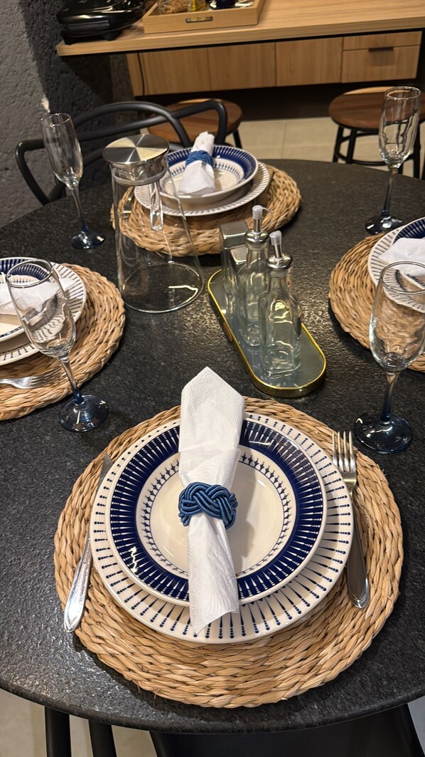 A table set with blue and white plates, a woven placemat, a folded napkin, and a glass.
