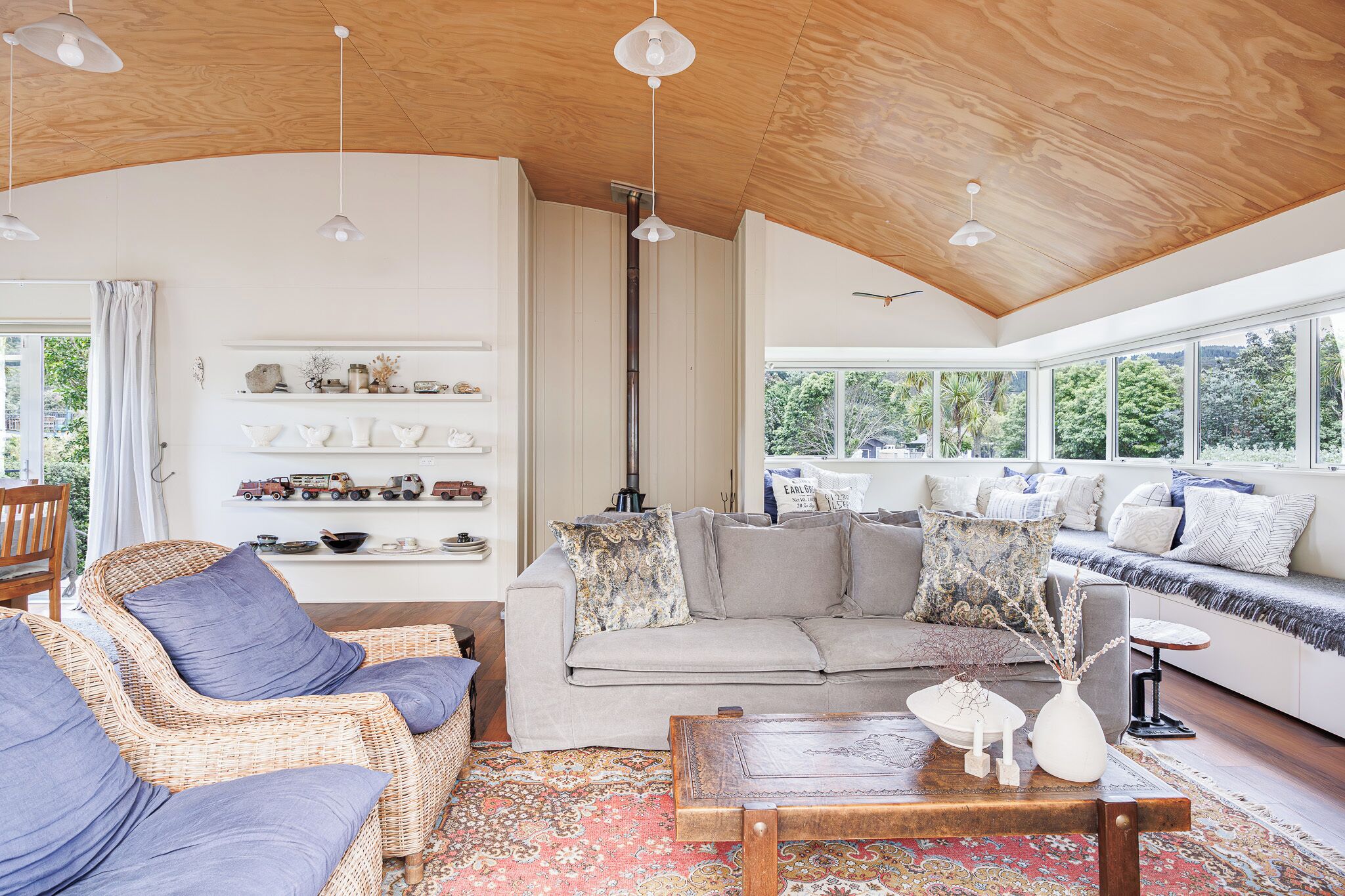 A spacious living room with a high ceiling, a sofa set, wicker chairs, a coffee table, and a fireplace.