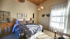 A bedroom with a bed, a dresser, a lamp, and a window with curtains.