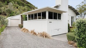 A modern white building with a garage, a covered patio area, and a gravel driveway.