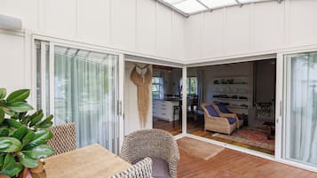 A modern interior with a dining area, a seating area with wicker furniture, and a kitchen visible through an open door.