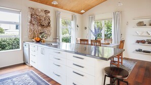 A modern kitchen with a central island, white cabinetry, and a wooden ceiling.