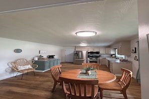 A dining area with a wooden table and chairs, a kitchen in the background, and a ceiling light fixture. - Summit Place - 10 Minutes to Ft Leonard Wood - Easy In and Out - Fenced Yard (Waynesville)