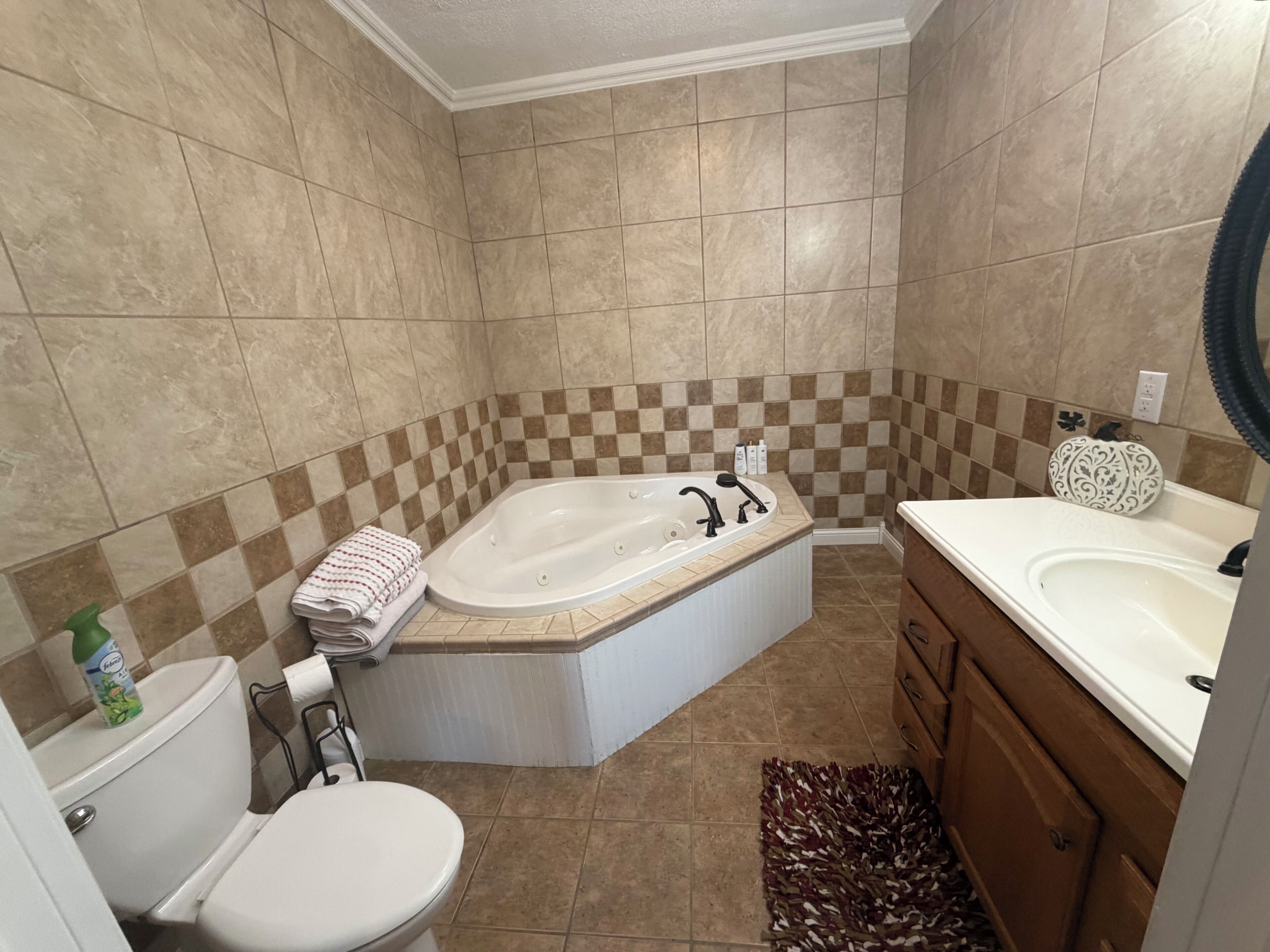 Een badkamer met bad, toilet, wastafel en een betegelde muur met een geruit patroon.