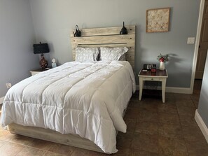 A bedroom with a bed, a nightstand, a wall clock, and a small table with a vase. - Patriots Peak stuns in every season! (Saint Robert)