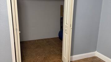 A room with a partially open door, brown tiled floor, and a blue exercise ball in the background.