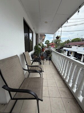 Ein Balkon mit zwei Stühlen, Blumentöpfen und einem weißen Geländer.