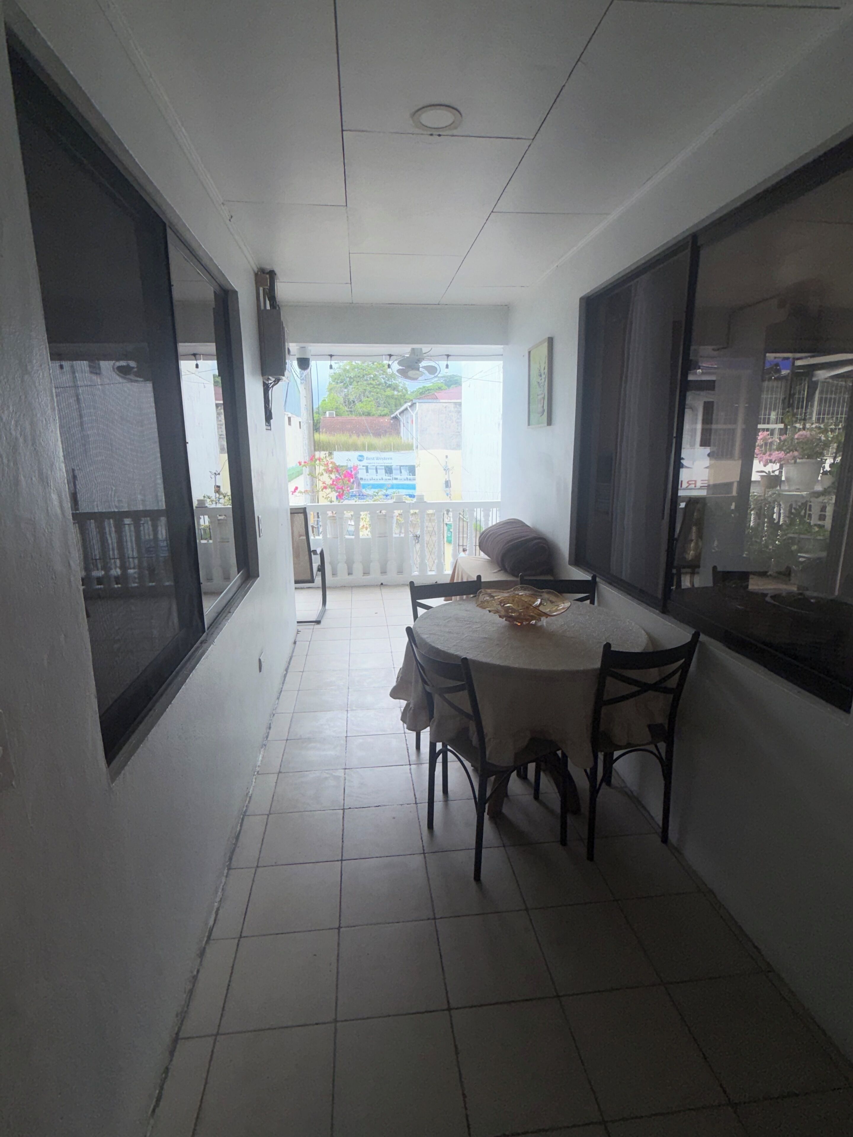 A narrow corridor with a dining table and chairs, a ceiling fan, and a view of the outside.