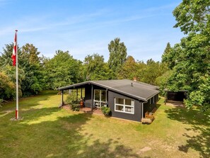 Une maison de plain-pied dotée d’un patio couvert, d’un mât pour drapeau et d’une pelouse bien entretenue.