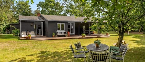 A house with a patio, outdoor seating, and a lawn.