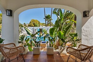 Eine Terrassenfläche mit zwei Korbstühlen, einem Pool und tropischen Pflanzen.