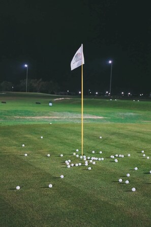 A golf course at night with a flag on a pole and scattered golf balls. - NOK Elegant 3BR Villa with Private Pool (Punta Cana)