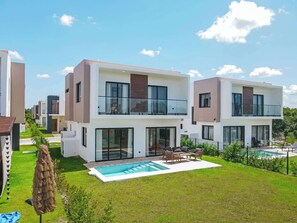A modern two-story residential building with a swimming pool, outdoor seating, and a well-maintained lawn. - NOK Elegant 3BR Villa with Private Pool (Punta Cana)