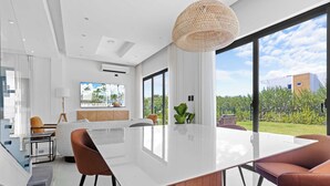 Ein modernes Interieur mit einem großen weißen Tisch, braunen Stühlen und einer hängenden Leuchte.