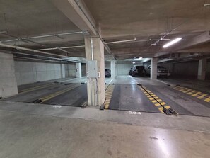 An underground parking garage with concrete pillars, marked parking spaces, and overhead lighting. - Cozy Loft with Panoramic View in Chihuahua (Chihuahua)