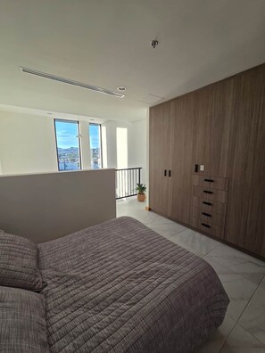 A modern bedroom with a large bed, a wardrobe, and a balcony with a view. - Cozy Loft with Panoramic View in Chihuahua (Chihuahua)