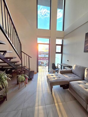 A spacious living area with a sofa, a dining table, and a staircase. - Cozy Loft with Panoramic View in Chihuahua (Chihuahua)