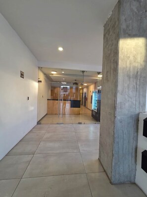A hallway with a glass door, a vending machine, and a concrete pillar. - Cozy Loft with Panoramic View in Chihuahua (Chihuahua)