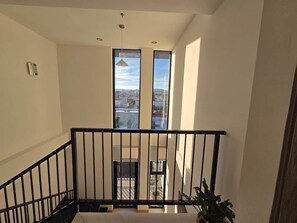 A staircase with a black railing leading to a balcony with large windows offering a city view. - Cozy Loft with Panoramic View in Chihuahua (Chihuahua)