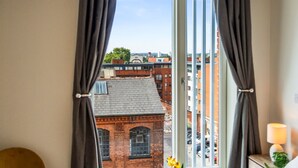 A room with a view of a cityscape through a window with curtains. - Stylish Central Birmingham 1Bed Apartment (Birmingham)