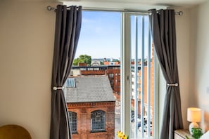 A room with a view of a cityscape through a window with curtains. - Stylish Central Birmingham 1Bed Apartment (Birmingham)