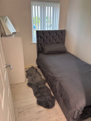 A bedroom with a bed, a wardrobe, a window with blinds, and a fluffy rug. - Dutchy’s Gest house sleeps 5 hot tub and steam room 2 car parking space (Liverpool)