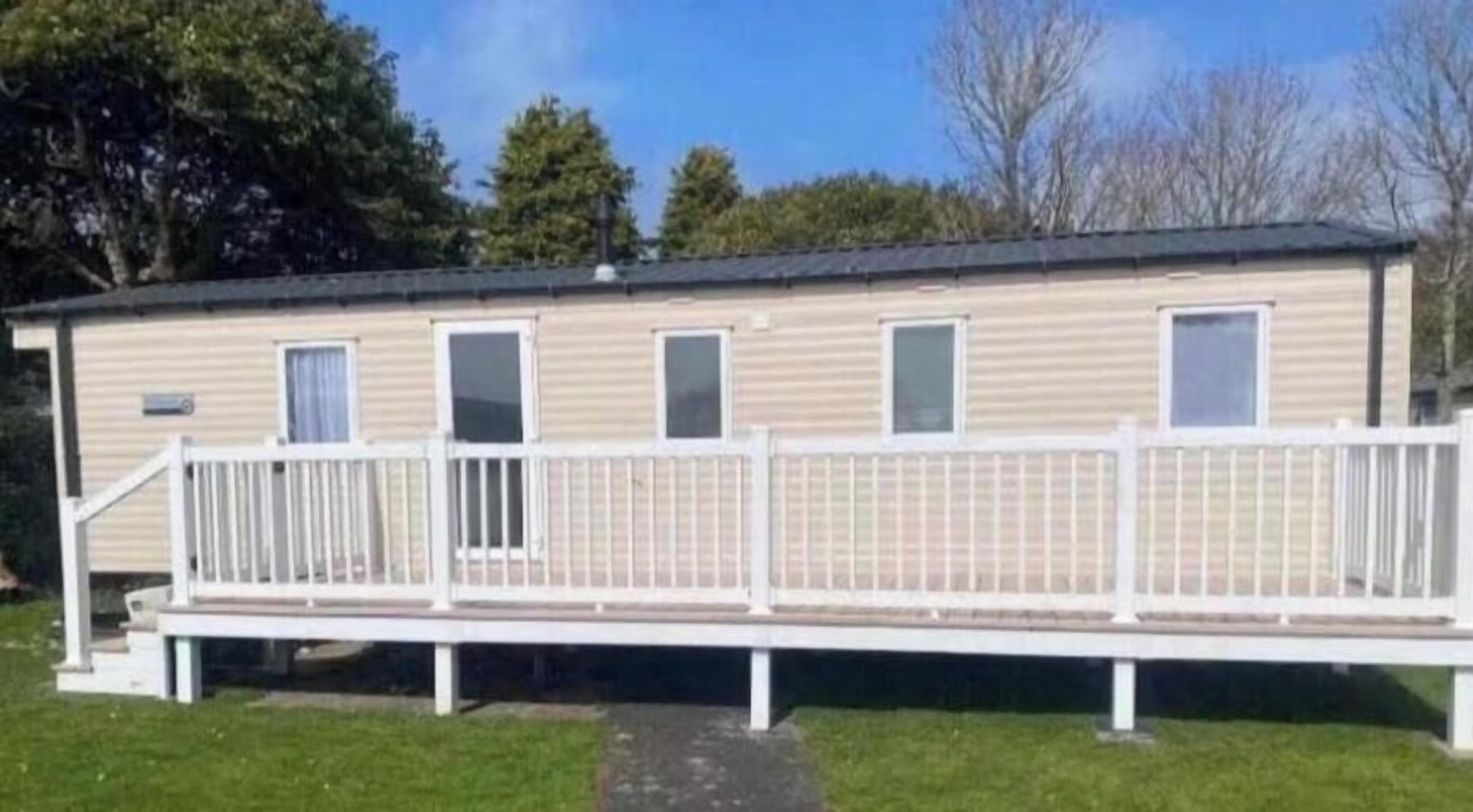 Una casa móvil con terraza cercada, varias ventanas y techo plano.