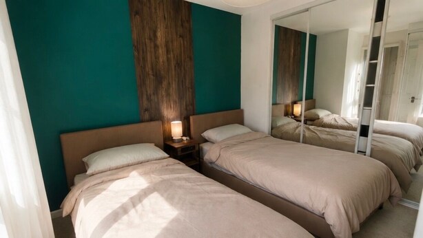 Quarto de hotel com duas camas, um espelho grande e uma parede de destaque em madeira.