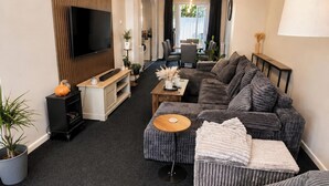 Uma sala de estar moderna com sofá, banquinho e unidade de entretenimento.