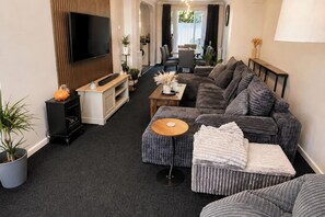 Ein modernes Wohnzimmer mit Sofa, Hocker und Unterhaltungseinrichtung.