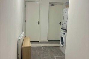 Ein Waschraum mit Waschmaschine, Trockner und einer Sitzbank.