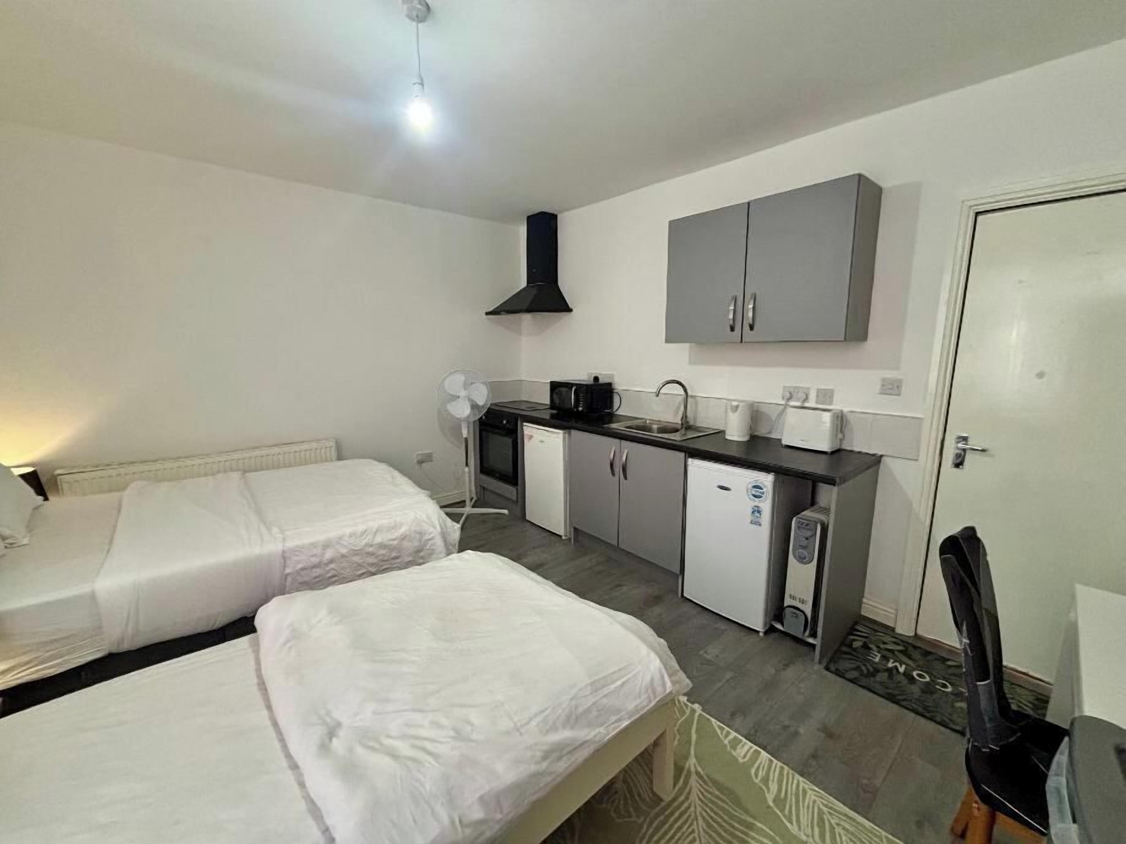 Ein kleines Hotelzimmer mit zwei Betten, einer Küchenzeile und einer Tür.