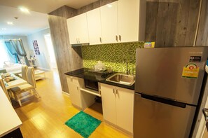 A compact kitchen with white cabinets, a stainless steel refrigerator, and a green tiled backsplash. - A105 Cozy 2-bedroom apartment with AC in a pleasant location (Huahin)