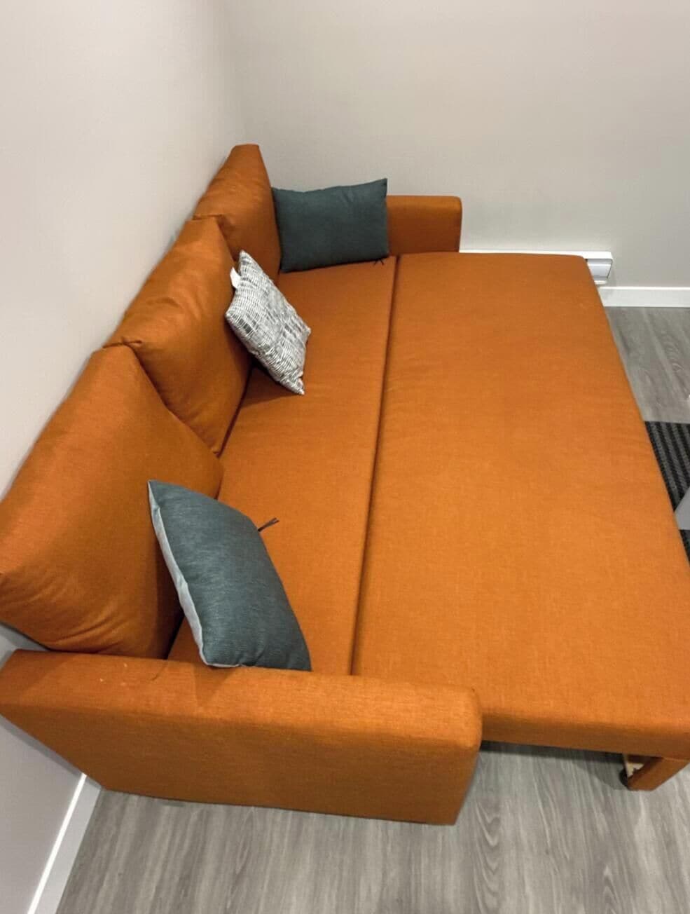 Ein Sofa mit einer hellen Wand und Holzboden.