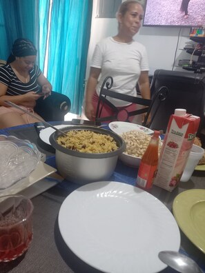 A dining table with various food items and a television in the background. - Room Flat apartment in beautiful Montego Bay with AC (Montego Bay)