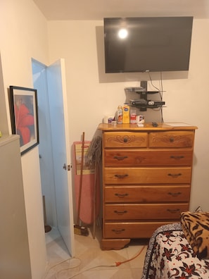 Ein Zimmer mit einem Holzkasten, einem an der Wand montierten Fernseher und einer Tür zu einem anderen Raum.