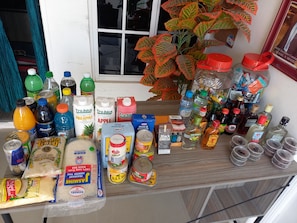 Verschiedene Lebensmittel und Getränke stehen auf einer Theke, darunter Flaschen, Dosen und verpackte Waren.