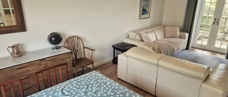 A living room with a sofa, a dining table with a polka dot tablecloth, a wooden chair, a small side table, and a globe.