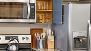 A kitchen with a microwave, stove, refrigerator, and various utensils. - Luxury 4-bedroom house for family fun, Pool, 10 mins to Disney (Kissimmee)