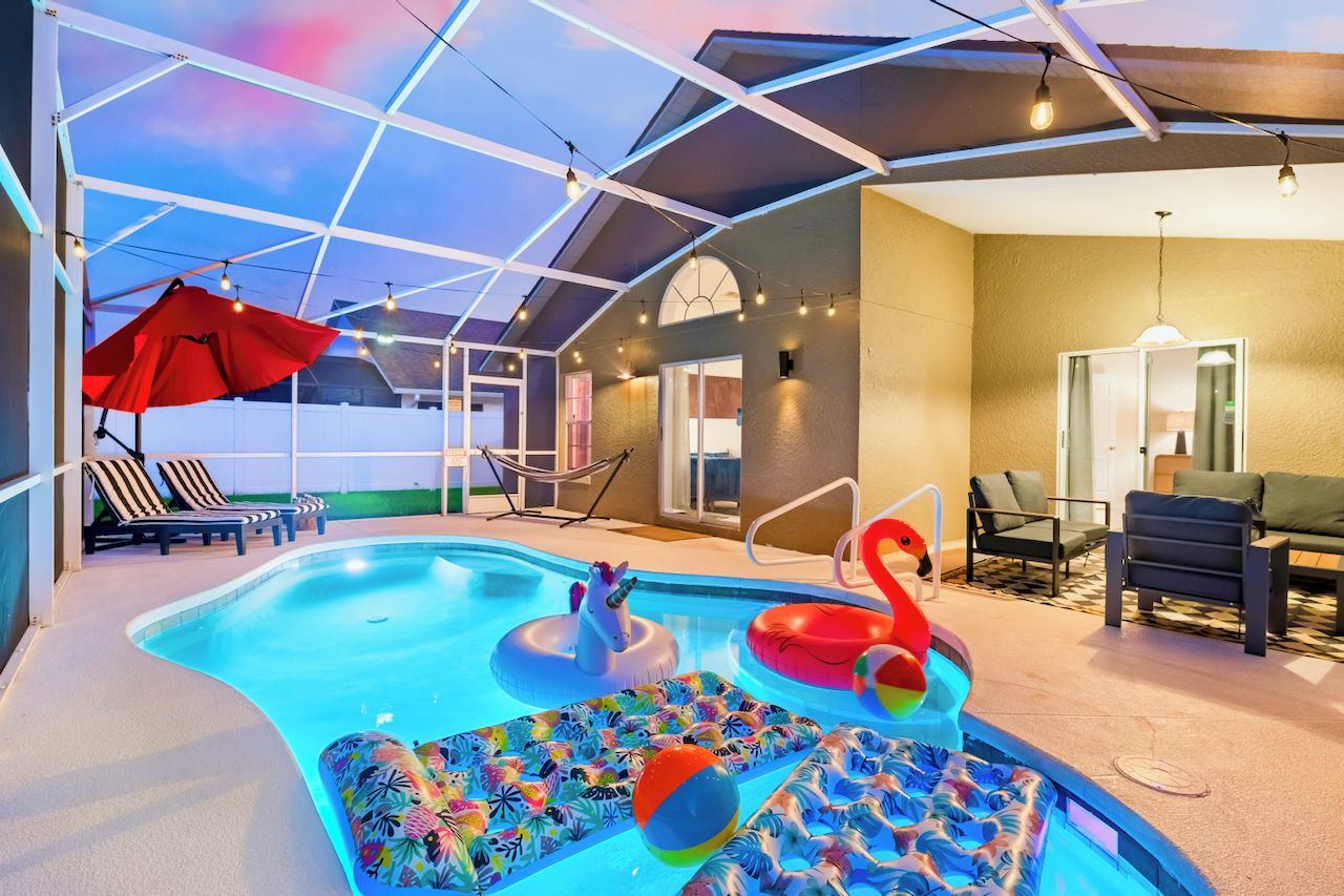 Une piscine avec des jeux gonflables, des chaises longues et un espace patio couvert.